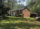 A quaint brick home with black shutters, a white columned front porch, and lush greenery in a verdant lawn at 184 Pine E St, Lillington, NC 27546