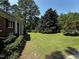 The front yard boasts lush green grass and mature trees surrounding a charming brick home at 184 Pine E St, Lillington, NC 27546