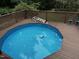 Above-ground swimming pool surrounded by a wooden deck and green foliage at 184 Pine E St, Lillington, NC 27546