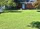 Grassy backyard with brick house featuring a back door, bench and mature trees for shade at 1917 New Hill Olive Chapel Rd, New Hill, NC 27562
