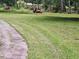 Backyard with a lawn mower on green grass with a pond in the background surrounded by trees at 1917 New Hill Olive Chapel Rd, New Hill, NC 27562