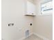 Bright laundry room with white cabinets, utility connections, and patterned tile flooring at 195 N Smith St, Clayton, NC 27520