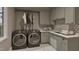 A modern laundry room features shaker cabinets, dark gray front load washer and dryer, and geometric backsplash at 725 Catawba St, Raleigh, NC 27609