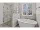 Luxurious bathroom featuring a soaking tub, glass-enclosed shower, and a large window with natural light at 30 Chestnut Oak Dr, Youngsville, NC 27596
