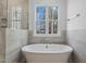 Relaxing bathroom view featuring a soaking tub, glass-enclosed shower and a picture window at 30 Chestnut Oak Dr, Youngsville, NC 27596