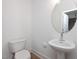 Clean bathroom with pedestal sink, toilet, and round mirror at 3911 Willow Gate Way, Raleigh, NC 27604