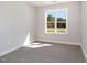 Well-lit bedroom with carpeted floors and a large window overlooking the wooded backyard at 607 Tuscany Cir, Princeton, NC 27569