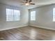 Bright bedroom features wood floors, a ceiling fan, and windows providing natural light at 428 Fast Pitch Ln, Four Oaks, NC 27524