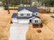 Aerial view featuring a gray two-story home with a three-car garage, concrete driveway, and landscaping at 7404 Prato Ct, Wendell, NC 27591