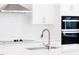 Modern kitchen with stainless steel faucet, white cabinets, quartz countertops, and subway tile backsplash at 7404 Prato Ct, Wendell, NC 27591