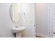 Bright powder room featuring pedestal sink, oval mirror, and neutral color palette at 398 Fast Pitch Ln, Four Oaks, NC 27524