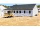 Rear exterior view of a home with light siding, dark roof and a covered porch at 472 Barbour Farm Ln, Four Oaks, NC 27524