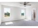 Bedroom featuring two windows overlooking backyard, neutral carpet, ceiling fan, and ensuite bathroom at 644 Barbour Farm Ln, Four Oaks, NC 27524