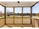 Cozy screened-in porch with wood flooring, railing, and a picturesque view of the wooded scenery at 674 Barbour Farm Ln, Four Oaks, NC 27524