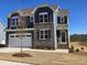 Two-story house with gray siding, stone accents, and a white garage door at 1109 Prominence Dr., Homesite 17, Durham, NC 27712