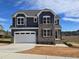 Two-story house with gray siding, stone accents, and a white garage door at 1109 Prominence Dr., Homesite 17, Durham, NC 27712