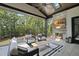 Covered patio area with an outdoor fireplace, TV, comfortable seating, and a view of the trees at 7417 Dover Hills Dr, Wake Forest, NC 27587