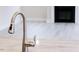 Close up of a kitchen faucet with a living area with fireplace in the background at 370 Fast Pitch Ln, Four Oaks, NC 27524