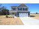 Charming two-story home with gray siding, black shutters, and an attached two-car garage at 335 Tobacco Barn Dr, Angier, NC 27501