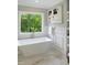 Bright bathroom featuring a freestanding tub, window view, elegant marble floors, and modern artwork at 2506 Silas Peak Ln, Apex, NC 27523