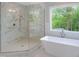This bathroom has a stand alone tub and a walk-in shower with marble and a window at 2506 Silas Peak Ln, Apex, NC 27523