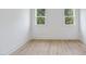 This is a bedroom with hardwood floors and two windows overlooking a wooded area at 2506 Silas Peak Ln, Apex, NC 27523