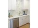 Bright modern kitchen featuring white cabinets, white tile backsplash, and stainless steel dishwasher at 2506 Silas Peak Ln, Apex, NC 27523