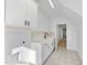 Bright laundry room with white cabinets, quartz countertop, black fixtures, and patterned floor at 2506 Silas Peak Ln, Apex, NC 27523