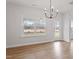 Well-lit dining area featuring hardwood floors, large windows, a modern chandelier, and access to the backyard at 124 August Pond Way # 138, Raleigh, NC 27603