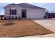 Beige house with a white garage door and landscaping at 1111 Woody Dr, Graham, NC 27253