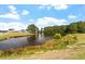 Scenic pond surrounded by lush greenery and houses on the horizon under a cloudy blue sky at 134 Black Walnut Dr # 205, Garner, NC 27529