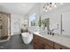 Elegant bathroom featuring a freestanding tub, double vanity, large mirrors, and modern lighting fixtures at 4800 Lakemont Dr, Raleigh, NC 27609