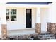 Inviting front porch with stone-clad columns and steps, leading to a black front door with sidelight window at 818 Barbour Farm Ln, Four Oaks, NC 27524