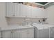 Laundry room with white cabinets, washer, dryer and a utility sink at 7220 Dime Dr, Raleigh, NC 27606
