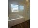 Bathroom featuring large soaking tub, glass enclosed shower, and a view from the large window at 135 Ironwood Blvd # 49, Youngsville, NC 27596