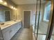 Bathroom featuring dual sinks, grey tiling, a window and glass shower door at 399 W Amber Oak Dr # 52, Selma, NC 27576