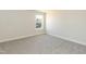 Bright bedroom with neutral walls, gray carpet, and a window overlooking the neighborhood at 135 Newport Lndg, Garner, NC 27529