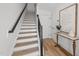 Hallway features wood stairs with black handrail, light wood floors, and decorative table at 700 W North St # 101, Raleigh, NC 27603