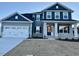 Two-story home with gray and blue siding, white garage doors, and stone accents at 84 Rosslyn Way # 92, Garner, NC 27529