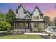 An exterior shot of a home with a gray brick facade, covered porch, and landscaping at dusk at 14020 Durant Rd, Raleigh, NC 27614