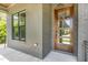 Charming covered porch with a modern wood and glass front door framed by gray brick and a window at 14020 Durant Rd, Raleigh, NC 27614