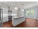 Open kitchen boasts white cabinets, stainless steel appliances, island, and pendant lighting, seamlessly connecting to dining area at 100 N Ridge View Way, Franklinton, NC 27525