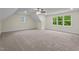 Spacious bonus room featuring carpet, natural light from windows, and a modern ceiling fan at 225 Whistlers Cv, Louisburg, NC 27549