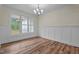 Dining room with natural light, wainscoting, and elegant chandelier over hardwood floors at 225 Whistlers Cv, Louisburg, NC 27549