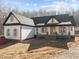 Stunning white farmhouse with a dark roof, welcoming porch, and stone accents at 2817 Silk Hope Gum Springs Rd, Pittsboro, NC 27312