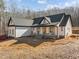 Stunning white farmhouse with a dark roof, welcoming porch, and stone accents at 2817 Silk Hope Gum Springs Rd, Pittsboro, NC 27312