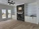 Bright living room featuring a stone fireplace, hardwood floors, and built-in shelving at 2817 Silk Hope Gum Springs Rd, Pittsboro, NC 27312