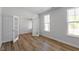 Sunlit bedroom featuring hardwood floors and bright windows with a doorway to another room at 119 Augusta Pond Way # 147, Raleigh, NC 27603