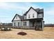 New construction two-story home with gray siding, black trim, and a covered front porch at 100 Firefly Ln, Louisburg, NC 27549