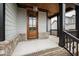 Covered front porch with stained wood door, brick steps, and black railing at 100 Firefly Ln, Louisburg, NC 27549